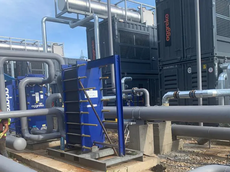 Conducte tehnologice gri lângă grupurile de generare Aggreko și un schimbător de căldură albastru